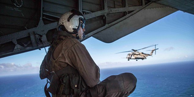 Crewman watching a helicopter over the sea